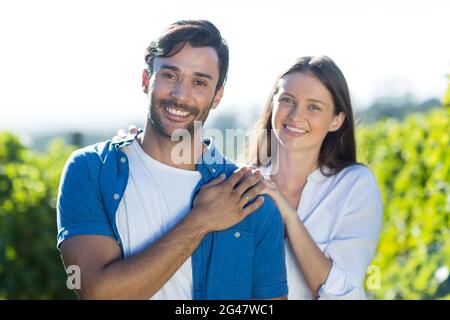 Porträt eines glücklichen jungen Paares, das am Weinberg steht Stockfoto