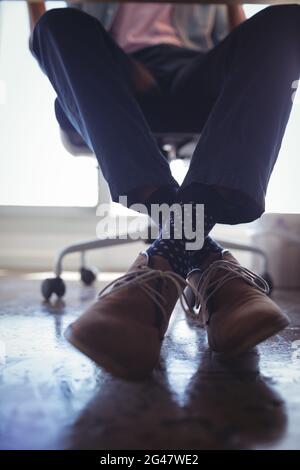 Unterer Teil des Geschäftsmannes, der im Büro auf einem Stuhl sitzt Stockfoto