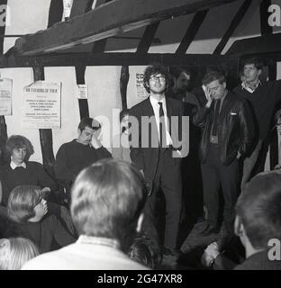 1970, historische, Volksmusik, in einem hölzernen Balkenraum in einem Pub, Leute stehen herum und warten darauf, dass ein Volkssänger aufsteht und aufführt, The Castle, Essex, England, Großbritannien. Werbeplakat an der Wand, das den 'an Evening of Folk' mit den Schwestern Shirley & Dolly Collins, Dave & Toni Arthur, Bob & Carol Pegg und Dave & Dave am Stevenage College of Further Education, gefördert vom Red Lion Folk Club, bewirbt. Stockfoto