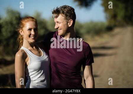 Junge Frau mit Mann, der am sonnigen Tag auf dem Bauernhof steht Stockfoto