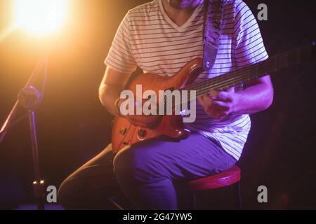 Mittlerer Abschnitt des Sängers, der Gitarre im Nachtclub spielt Stockfoto