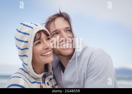 Lächelndes Paar mit Kapuzenpullover, während es wegschaut Stockfoto