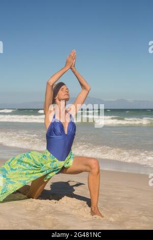 Frau mit erhobenen Armen praktiziert Yoga gegen klaren Himmel Stockfoto