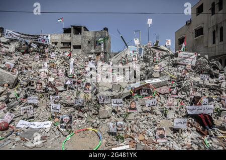 Gaza, Palästina. Juni 2021. Ein Mädchen sitzt neben Bildern von Kindern, die bei den israelischen Angriffen auf Gaza ihr Leben verloren haben. Fotos der Kinder wurden über den Trümmern des Hauses der Familie Sakka in Khan Yunis, Gaza, aufgestellt, das im vergangenen Monat während 11 Tagen der Gewalt von der israelischen Armee zerstört wurde. (Foto von Yousef Masoud/SOPA Images/Sipa USA) Quelle: SIPA USA/Alamy Live News Stockfoto