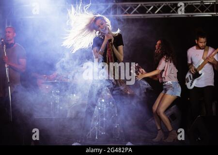 Fröhliche Sängerin mit Musikern, die während des Musikfestivals auftreten Stockfoto