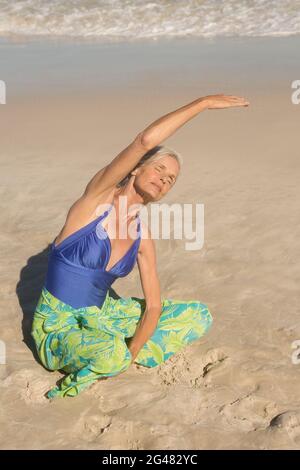 Hohe Armreif Ansicht der Frau beim Training, während sie auf Sand sitzt Stockfoto