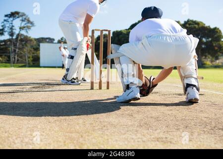 Rückansicht des Wicket-Keepers, der während des Spiels an Stumps hocke Stockfoto