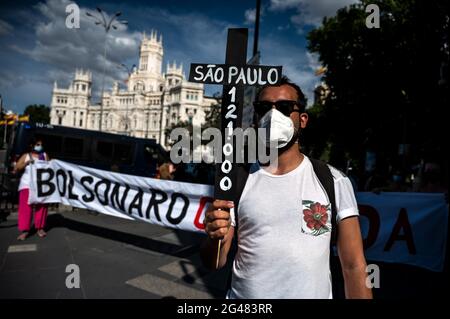 Madrid, Spanien. Juni 2021. Ein Protestant, der ein Kreuz trägt, das die Anzahl der Todesfälle durch das Coronavirus in Sao Paulo während einer Demonstration gegen den brasilianischen Präsidenten Jair Bolsonaro zeigt, gegen die Bekämpfung der Pandemie protestiert und die Liberalisierung von Patenten für Impfstoffe gegen COVID-19 fordert. Quelle: Marcos del Mazo/Alamy Live News Stockfoto