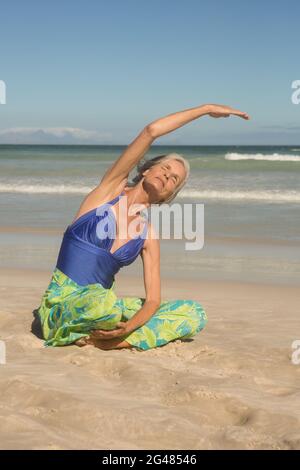 Nahaufnahme einer Frau, die Yoga praktiziert, während sie auf Sand sitzt Stockfoto