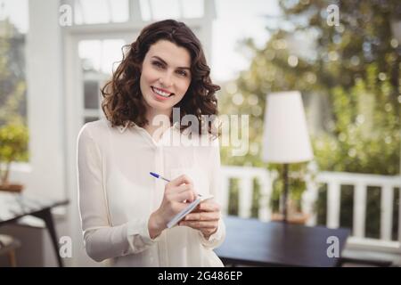 Lächelnde Kellnerin schrieb auf Notizblock im Restaurant Stockfoto