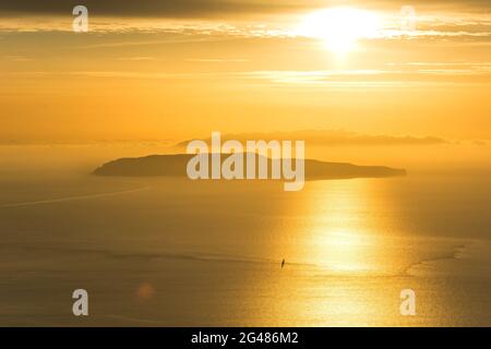 Kleine Insel und einsames Segelboot auf dem Meer während dramatischen goldenen Sonnenuntergang in der Nähe der Küste von Trapani, auf Sizilien, Italien Stockfoto