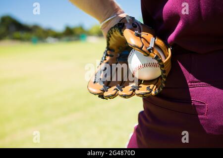 Mittelteil des Baseballkännchen, der den Ball in Handschuhen hält Stockfoto