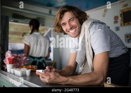 Porträt eines Kellners, der auf einem Notizblock an der Theke schrieb Stockfoto