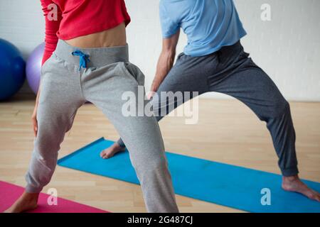 Unterer Abschnitt des männlichen Ausbilders, der mit einer weiblichen Schülerin im Club trainiert Stockfoto