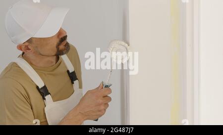 Hand des Malers Mann Dekorateurin Arbeit des Hauses zu renovieren, mit Rollenfarbe, Fensterbefestigung als Hintergrund, Nahaufnahme Stockfoto