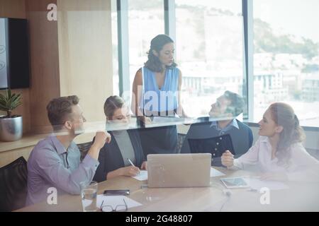 Geschäftspartner diskutieren in Treffen durch Glas gesehen Stockfoto