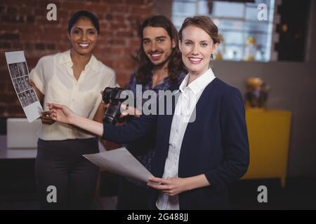 Porträt eines lächelnden jungen kreativen Teams, das über Collage diskutiert Stockfoto