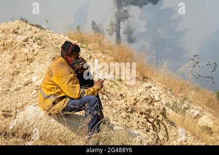 Mevasseret Zion, Israel - 19. Juni 2021: Ein junger Feuerwehrmann, der eine Pause macht, während er einen Waldbrand an der Stadtgrenze einer Stadt in der Nähe von Jer bekämpft Stockfoto