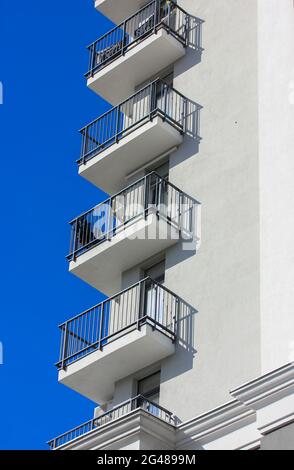 Das Äußere eines modernen Luxus-Apartmentgebäudes in der Stadt. Balkone eines neu gebauten Hauses mit schwarzen Metallgittern und kontrastierenden Schatten auf einem Su Stockfoto