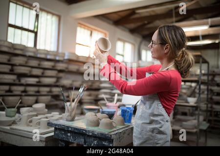 Frau überprüft Becher an der Arbeitsplatte Stockfoto