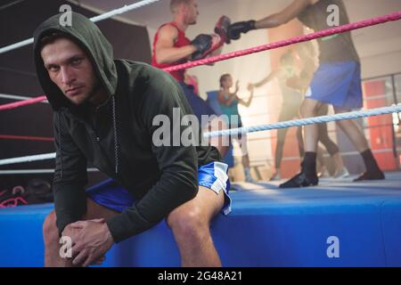Porträt des jungen männlichen Boxer sitzen auf Boxring im Fitness-studio Stockfoto