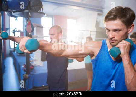 Junge männliche Athleten schlagen mit Hanteln Stockfoto