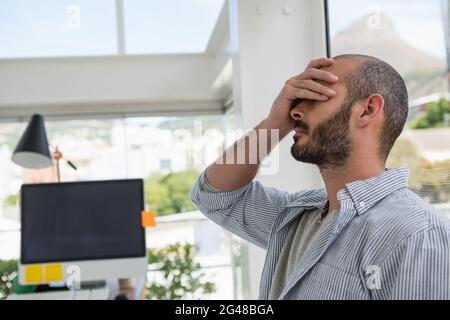 Frustrierter Designer, der sich an ein Glasfenster lehnt Stockfoto