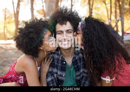 Frauen küssen junge männliche Freunde Stockfoto