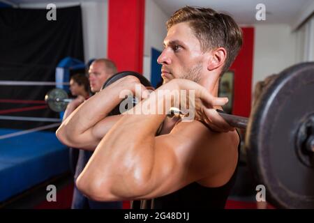 Junger männlicher Athlet, der die Langhantel hebt Stockfoto