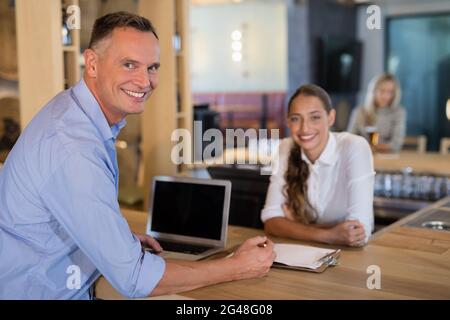 Lächelnder Manager und Barkeeper stehen an der Theke Stockfoto