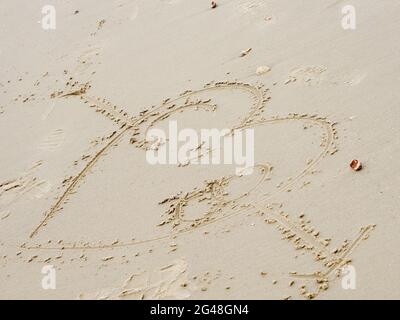 Ein Pfeil mit einem Herz durch ihn gezogen in den Sand Stockfoto
