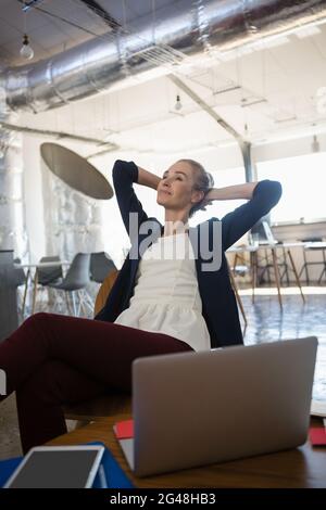 Geschäftsfrau mit Händen hinter dem Kopf, die sich im Büro entspannt Stockfoto