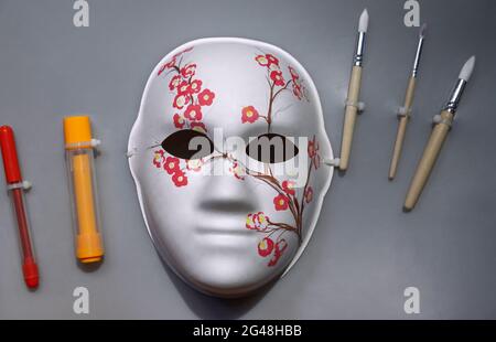 Kindermaske mit einem bemalten Sakura-Zweig. Maske, Pinsel, Filzstifte für die Kreativität der Kinder. Stockfoto