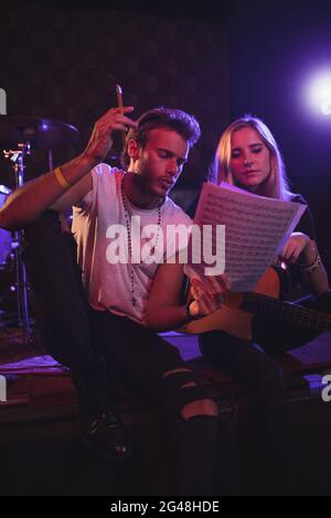 Männliche und weibliche Musiker üben mit Notenblättern im Nachtclub Stockfoto