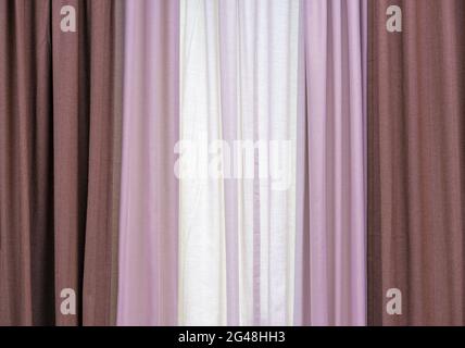 Dreilagige Vorhänge aus braunem, rosa und weißem Stoff. Stockfoto