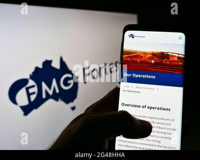 Person mit Mobiltelefon und Webseite des australischen Bergbauunternehmens Fortescue Metals Group auf dem Bildschirm mit Logo. Konzentrieren Sie sich auf die Mitte des Telefondisplays. Stockfoto