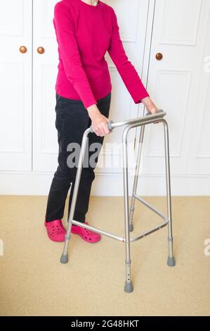 Alte Person mit Gehrahmen im Haus Stockfoto