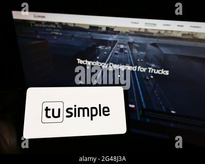 Person, die Mobiltelefon mit dem Logo des US-autonomen Fahrers TuSimple Holdings Inc. Auf dem Bildschirm vor der Webseite hält. Konzentrieren Sie sich auf die Telefonanzeige. Stockfoto