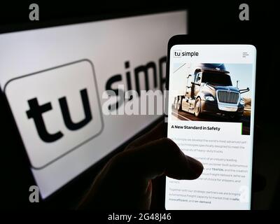 Person, die Mobiltelefon mit der Webseite des US-Autonomen Fahrers TuSimple Holdings Inc. Auf dem Bildschirm vor dem Logo hält. Konzentrieren Sie sich auf die Telefonanzeige. Stockfoto