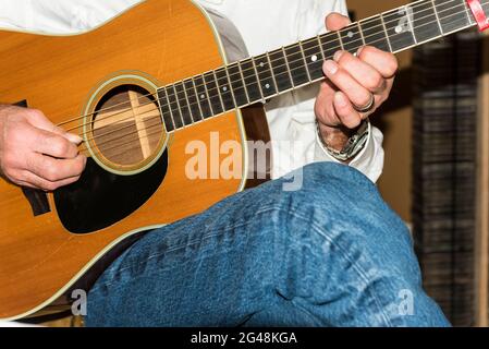 Detail der sitzenden männlichen Gitarristen Finger Kommissionierung einer Vintage MartinD 35 Akkusic Gitarre. Stockfoto