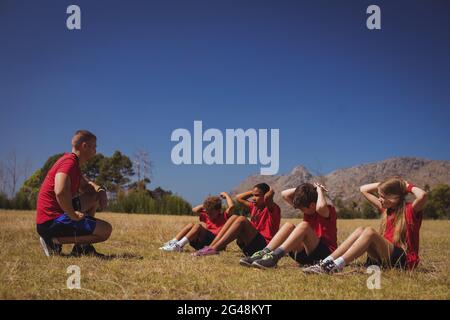 Trainer unterrichtet Kinder während des Trainings im Bootcamp Stockfoto