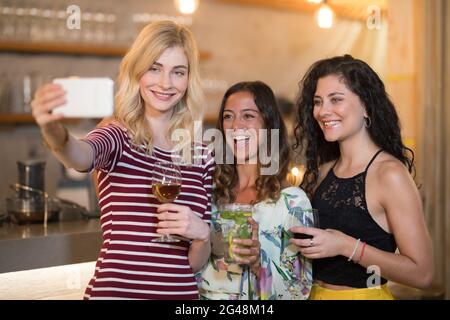 Portrait von weiblichen Freundinnen, die beim Trinken Selfie machen Stockfoto