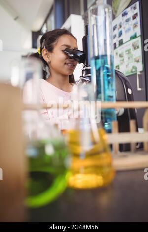 Grundschülerin mit Mikroskop im Labor Stockfoto