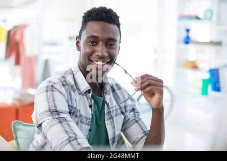 Lächelnder, männlicher Manager, der eine Brille im Büro hält Stockfoto