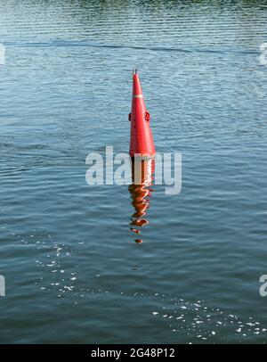 Schwimmende rote Navigationsboje auf blauem Wasser des Dnipro River. Boje im Fluss. Navigationsausrüstung. Ruhige Wasseroberfläche. Stockfoto