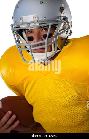 Porträt eines entschlossenen Fußballspielers, der den Ball mit einem Helm hält Stockfoto