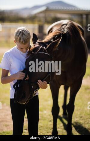 Lächelndes Mädchen streichelt das Pferd auf der Ranch Stockfoto