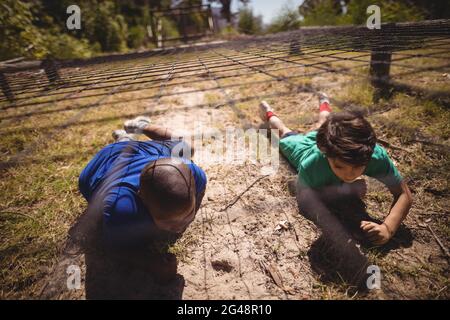 Kinder krabbeln während eines Hindernisparcours unter dem Netz Stockfoto