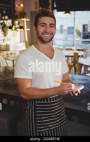 Porträt eines glücklichen Kellners, der die Bestellung annahm Stockfoto