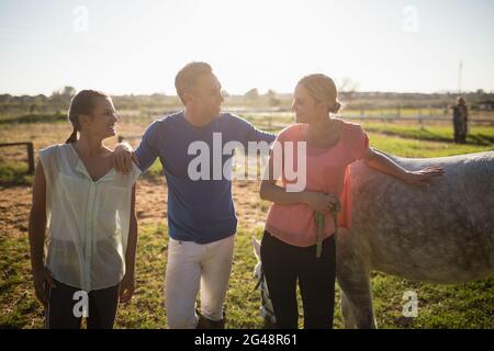 Männlicher Trainer, der mit Frauen spricht, während er zu Pferd steht Stockfoto